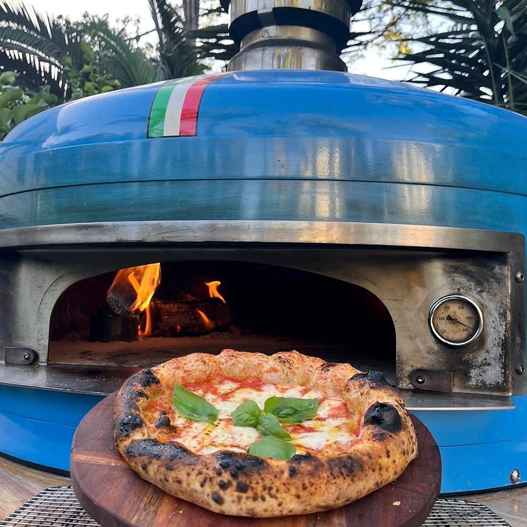 Wood-fired pizza cooking in the blue oven on the Antimo pizza truck