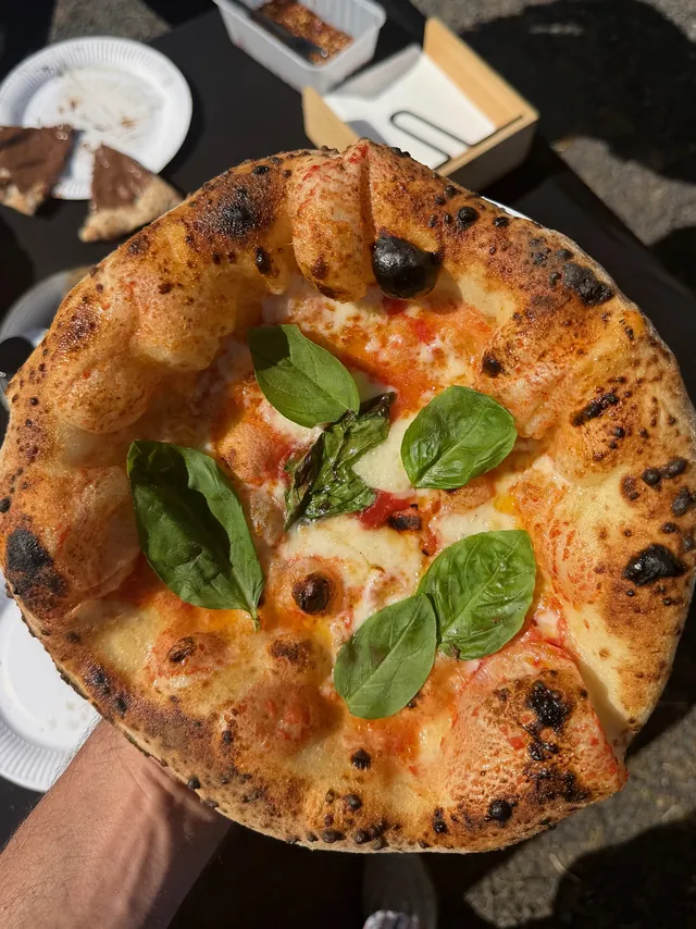 Close-up of a wood-fired Margherita pizza with fresh basil and charred crust