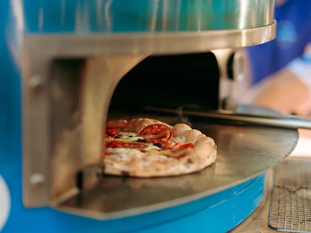 Pizza coming out of the blue wood-fired oven at a wedding